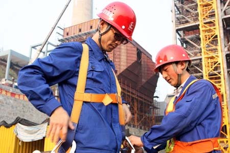進(jìn)入高空作業(yè)前，同事正在幫他穿戴高空安全帶